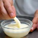 Manos expertas mezclando una crema en un bol de cristal, evocando el proceso artesanal de elaboración.