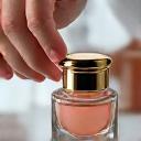 Producto cosmético siendo envasado a mano en un frasco de vidrio, mostrando atención al detalle.